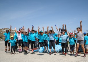 Mykonian school children jump for joy after helping to clean up Korfos Beach.